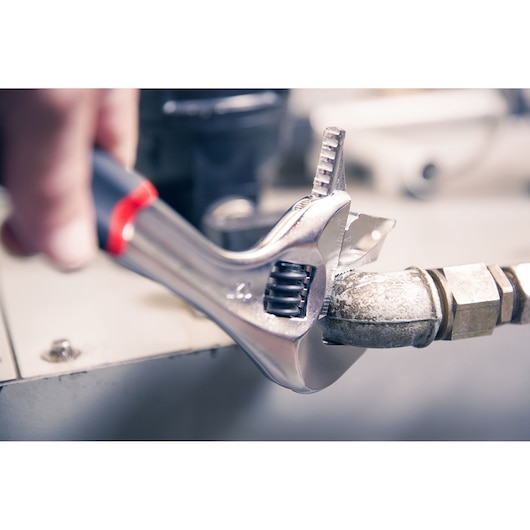 Facom adjustable wrench 101_15GR used on a metal pipe, close-up photo showing tool details.