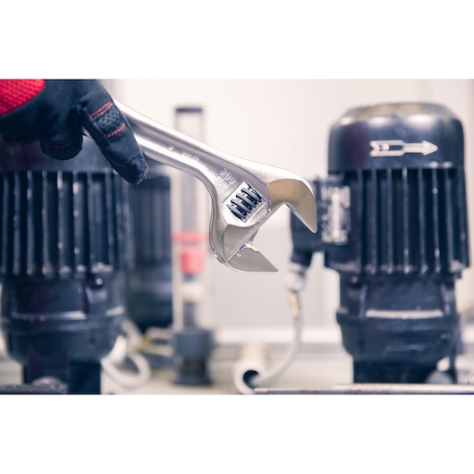 Photo of Facom adjustable wrench 101_15 held by gloved hand in industrial setting.