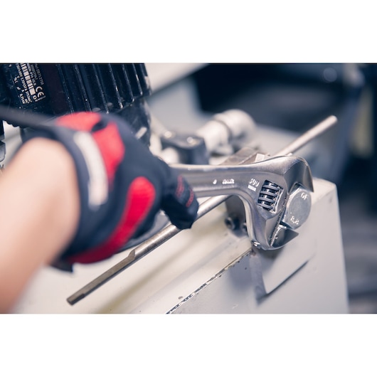 Facom 101_15 adjustable wrench tightening a metal bolt, close-up angle, worker in gloves using tool.