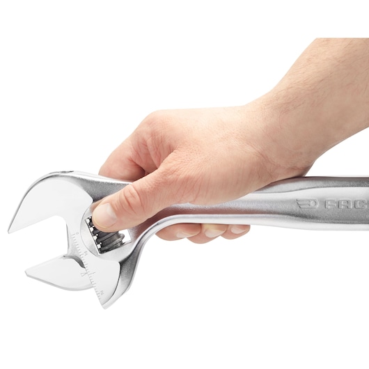 Photo of a hand holding a Facom adjustable wrench 101_18, silver color, side view on white background.