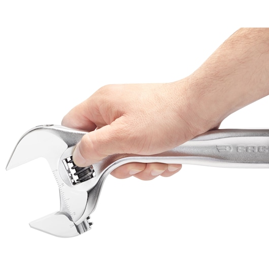 Photo of a hand gripping a Facom adjustable wrench 101_18, side view on white background.