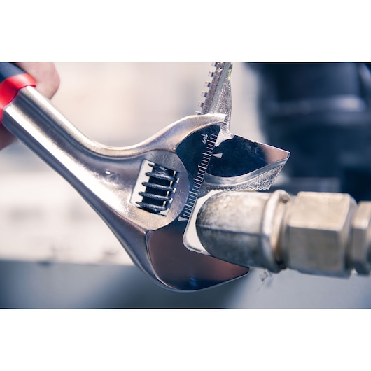 Facom adjustable wrench 101_8GR used on metal pipe fitting, close-up photography.
