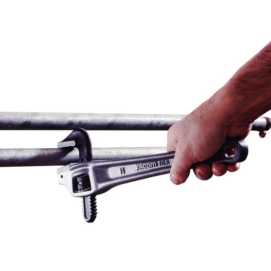 Facom 135A_14 pipe wrench in use tightening a metal pipe, side view.