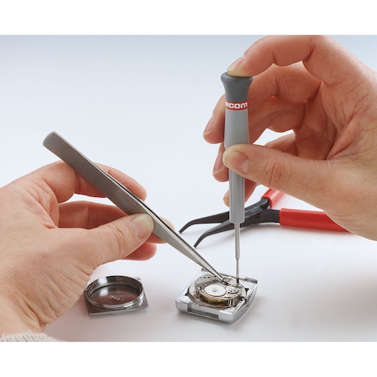 Facom 140AA precision screwdriver used to repair a watch mechanism, close-up on white background.