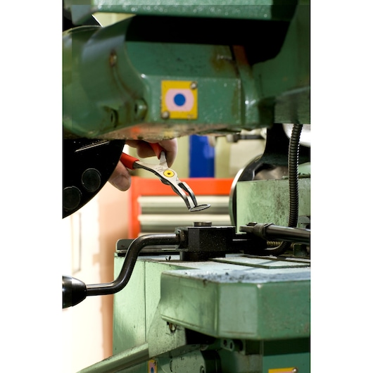 Facom 167A18 pliers with red handles being used to hold a metal part in industrial machinery.