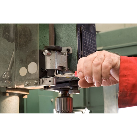 Photo of a hand using a Facom tool to adjust a metal machine, SKU 197A23, close-up view.
