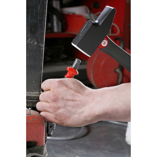 Photo of a hand using a Facom 200C_36 chisel with a hammer in a workshop setting.