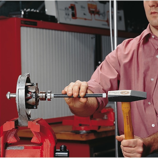 Facom 214_15 hammer used by a person for mechanical assembly in a workshop setting.