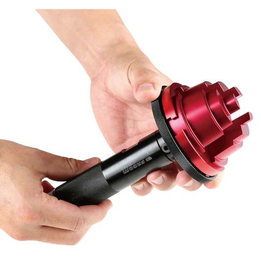 Photo of Facom 217.J2PB specialized tool with black handle and red multi-step head, held in hands, front angle.