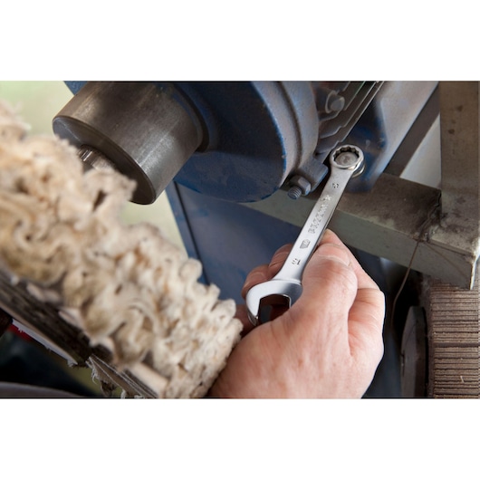 Photo of Facom 39_7 combination wrench in hand tightening a bolt on industrial machinery.