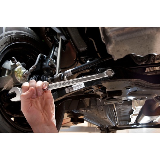Photo of a Facom 40_30LA combination wrench being used to tighten a bolt on a car suspension undercarriage.