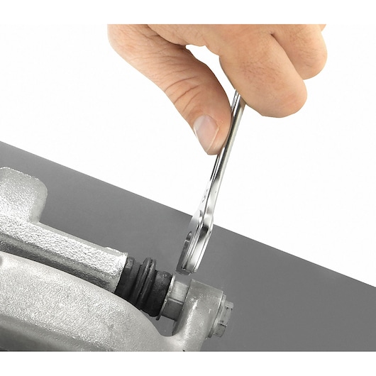 Facom 440_33 wrench in hand tightening a bolt on metal part, close-up angle.