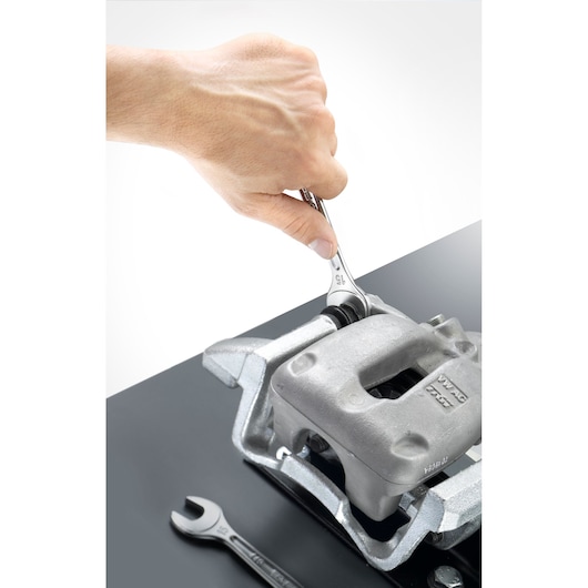 Photo of a hand using a Facom combination wrench 440_5_5H to tighten a bolt on a metallic automotive part.