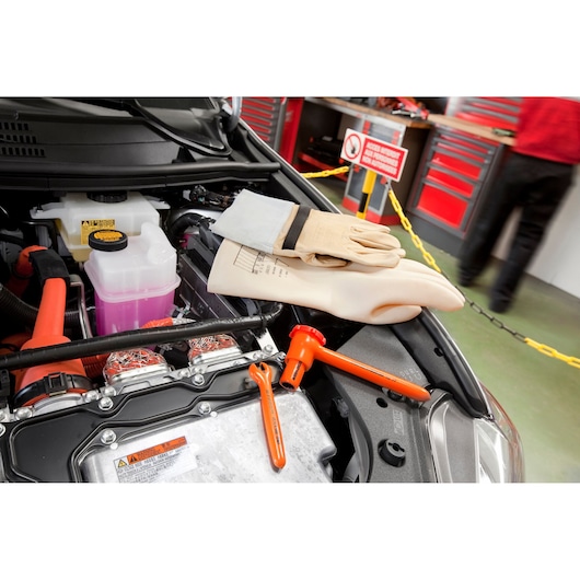 Facom insulated glove set 46_10AVSE for electrical safety, shown on a car engine bay with orange tools and gloves.