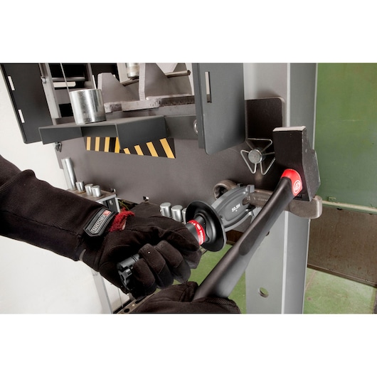 Photo of Facom 50_SH sledge hammer in use, held by gloved hand near industrial machine.