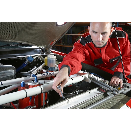 Facom 64_5_16X11_32 wrench used on car engine, mechanic in red jacket working under hood.