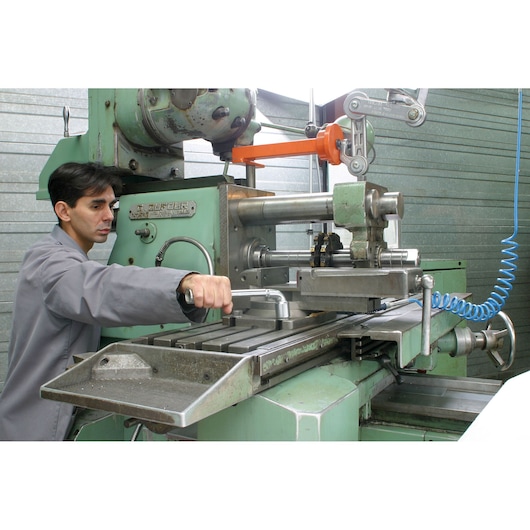 Facom 75_27 hand tool used to adjust part on industrial milling machine in workshop setting.