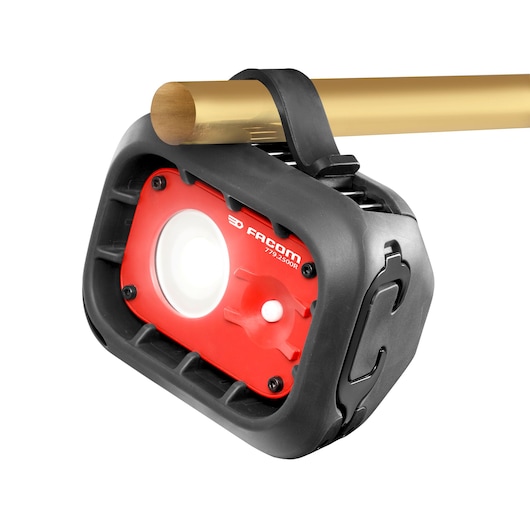 Facom 779.2500RPB work light with red front panel and black housing, attached to a metal pipe, front angle.