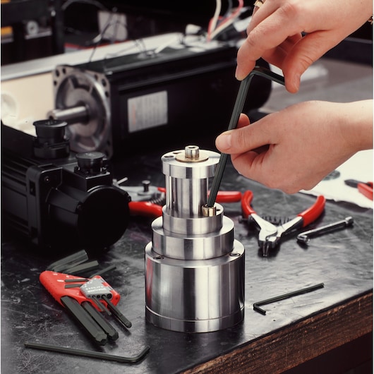 Facom 83H_6 hex key in use on industrial metal part, red hand tools in background, workshop setting.