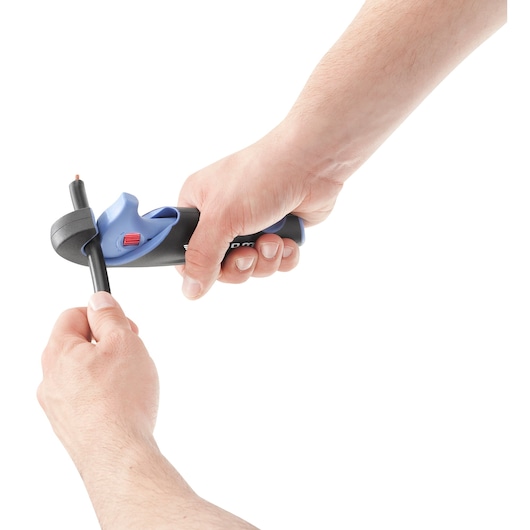 A person using a Facom tool to strip the insulation from an electrical cable, showing the tool held in one hand and the cable in the other against a white background.