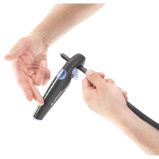 A close-up view of a person using a Facom tool to strip the insulation from an electrical cable.