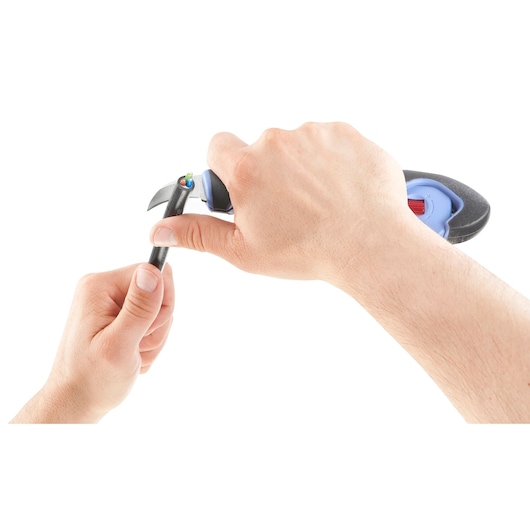 A pair of hands using a cable stripping tool to remove the insulation from a black electrical wire, exposing the colored wires inside.