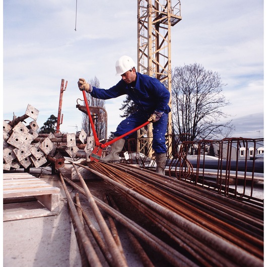 Facom 990_RB0 bolt cutter used by worker in construction site, cutting steel rods outdoors.