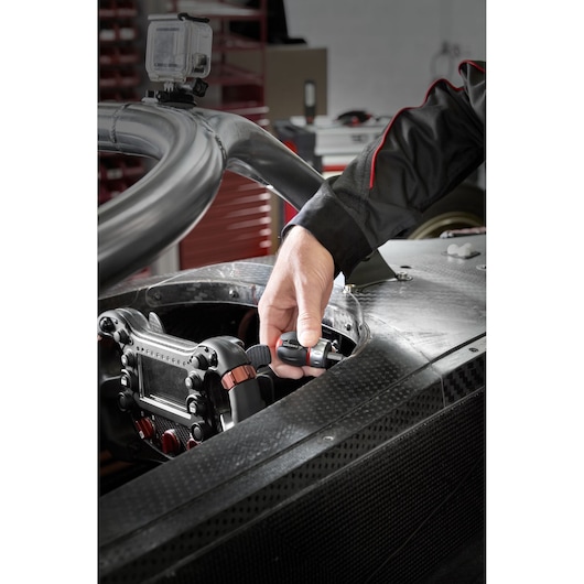 Facom ATCL.S stubby screwdriver in hand near race car steering wheel, workshop background.