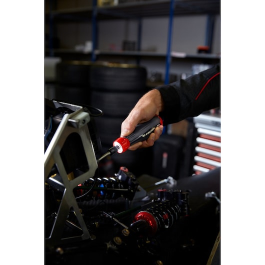 Facom ATPA4V.J12IPB insulated screwdriver with red and black handle in use on machinery.
