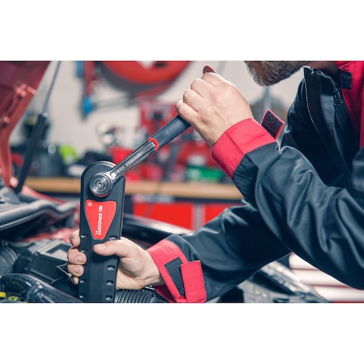 Photo of mechanic using Facom AXS.LPB torque wrench on car engine in workshop.
