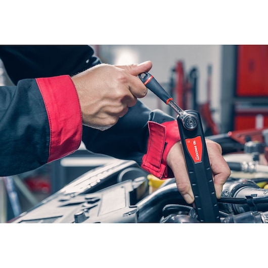 Facom ratchet tool AXS.LPB used by mechanic in workshop, close-up of hands and tool.