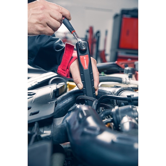 Facom AXS.LPB inspection lamp used by mechanic in car engine bay, close-up view.