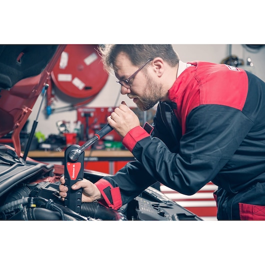 Photo of mechanic using Facom torque wrench AXS_M to tighten engine component in workshop.