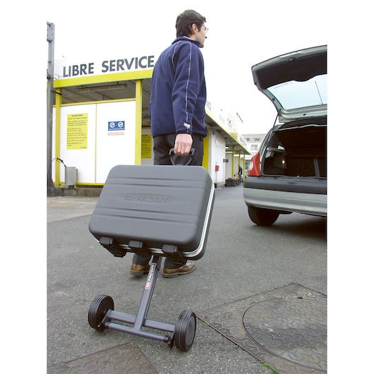 Facom BV_51A wheeled tool case being transported outdoors near a parked car, closed trunk visible.