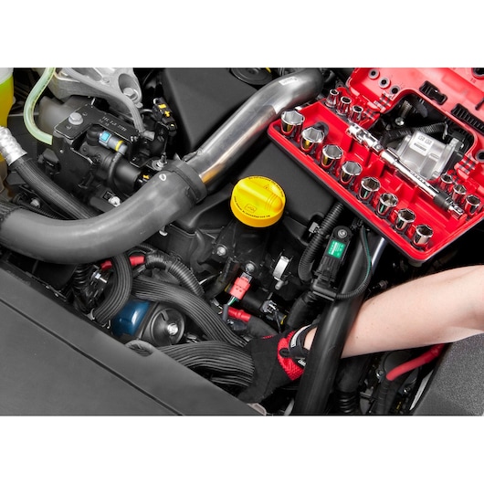 Facom C48-1 socket set in red tray used in car engine bay, showing sockets and ratchet during maintenance.