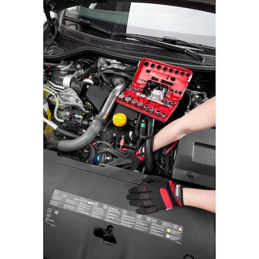 Facom C48-1 socket set in red case used on car engine by mechanic with gloves.
