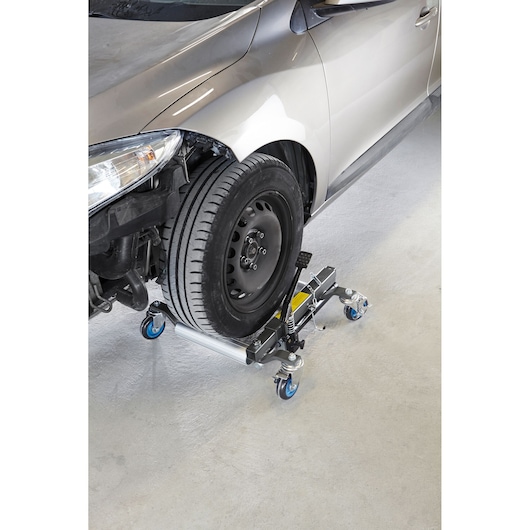 Facom CR_12H hydraulic wheel dolly with blue casters under a car front tire, angled view.