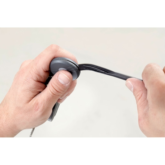 Facom CR.LPTPB tire lever tool held in two hands, close-up view, black plastic with grooved tip.
