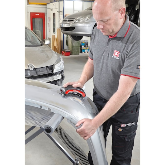 Facom CR_SBS sanding block held by technician working on car body panel in workshop.