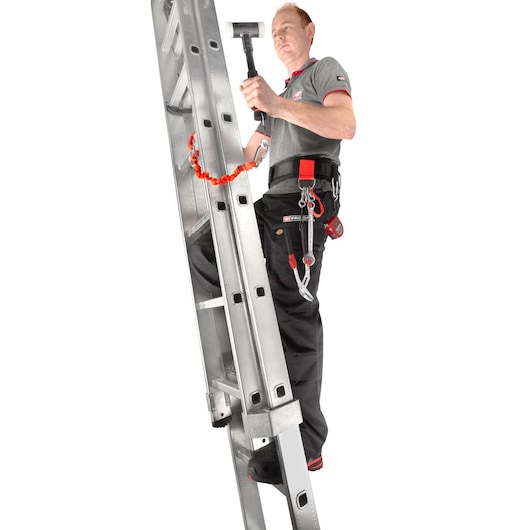 Photo of worker using Facom CT100-140 safety tool lanyard on ladder, holding a hammer, with harness and belt.