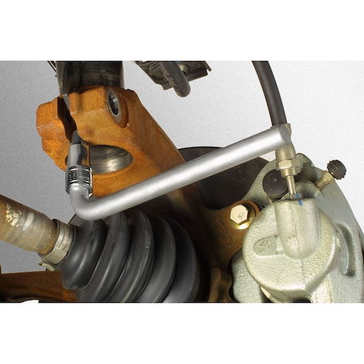 Facom DS_J5 brake bleeder wrench in use on a vehicle's brake caliper, close-up showing tool on bleeder valve.