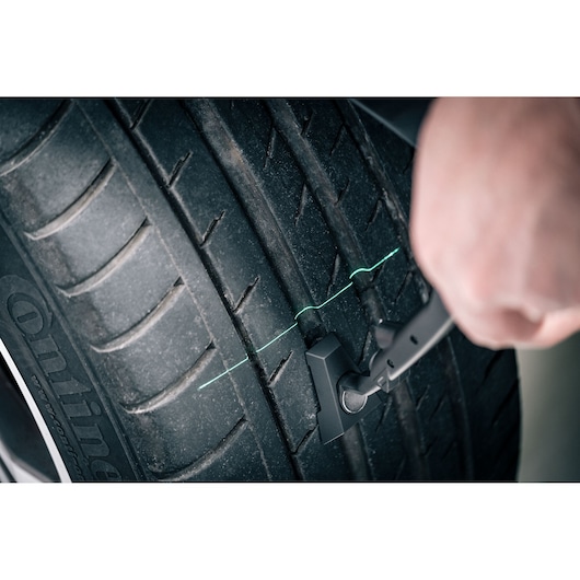 Facom DX_TSCANPB tire tread depth gauge measuring car tire, close-up photo.
