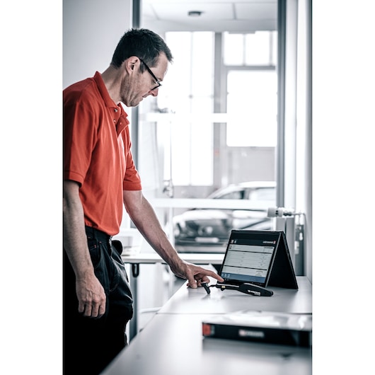 Facom DX_TSCANPB electronic scan tool with display, shown on a desk with technician in work environment.