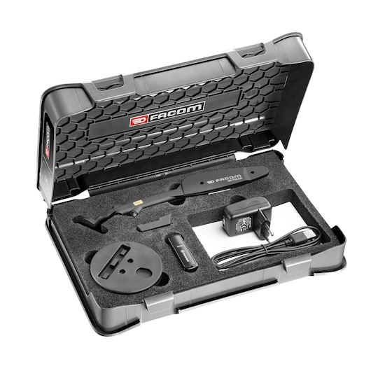 A black Facom branded hard case containing a photography tool kit. The kit includes a handheld device, a circular base, an adapter, a USB stick, and a power charger, all securely placed in foam compartments.