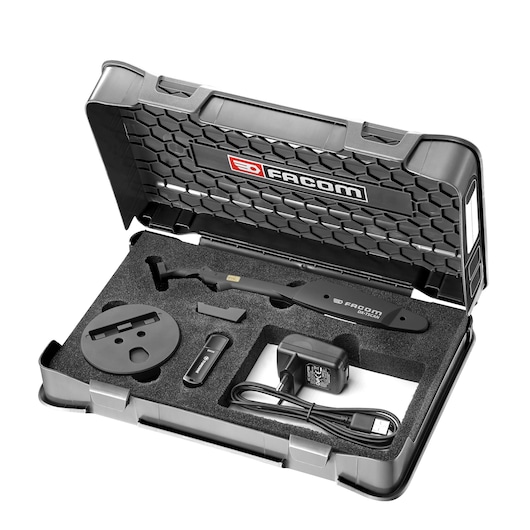 A Facom DX_TSCANPB_K2 photography tool kit displayed in an open hard plastic case. The case has a honeycomb pattern and Facom branding on the inside lid. The foam interior holds several components, including a handheld scanner, a charger with cable, a USB stick, a round mounting accessory, and other small parts.