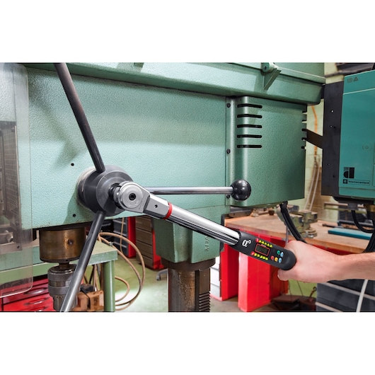 Facom E_316A200S digital torque wrench used on industrial machine in workshop setting.