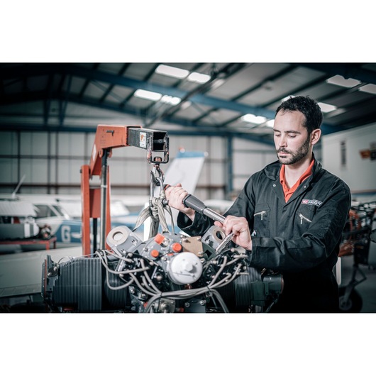 Photo of mechanic using Facom E_516ST-135PB torque wrench on aircraft engine in hangar.