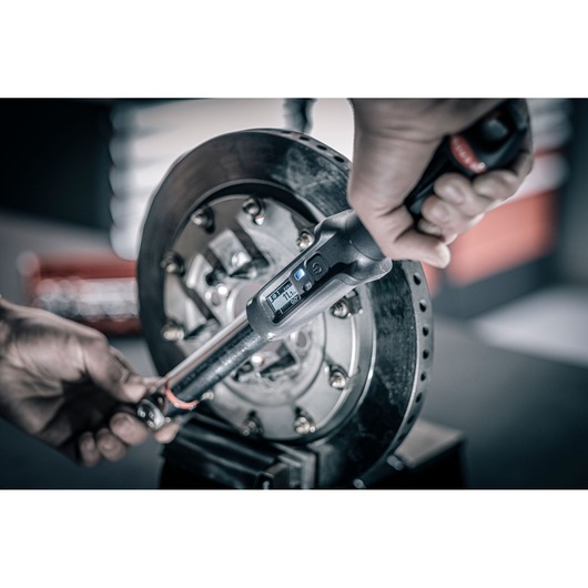 Facom E_516ST-135PB digital torque wrench used on a brake disc, close-up photography.