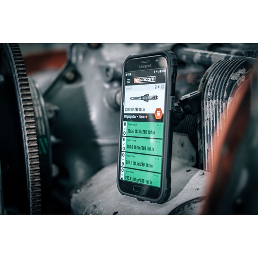 Photo of Facom E_516ST-135PB smartphone displaying torque measurement data in an industrial machine setting.
