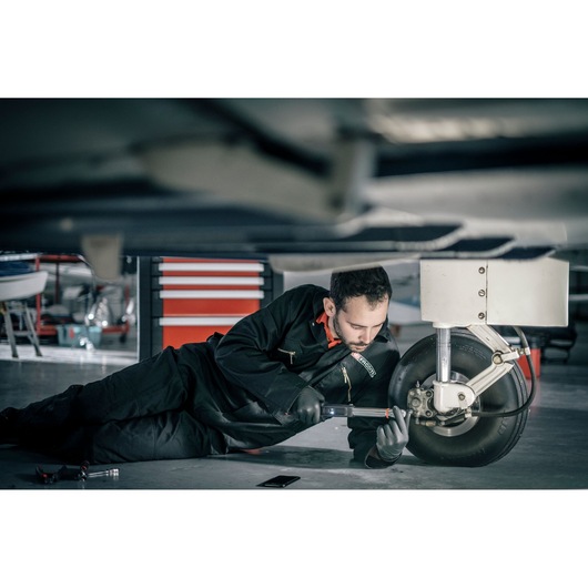 Facom E_516ST-30PB photography of technician in black coveralls servicing aircraft wheel in hangar.